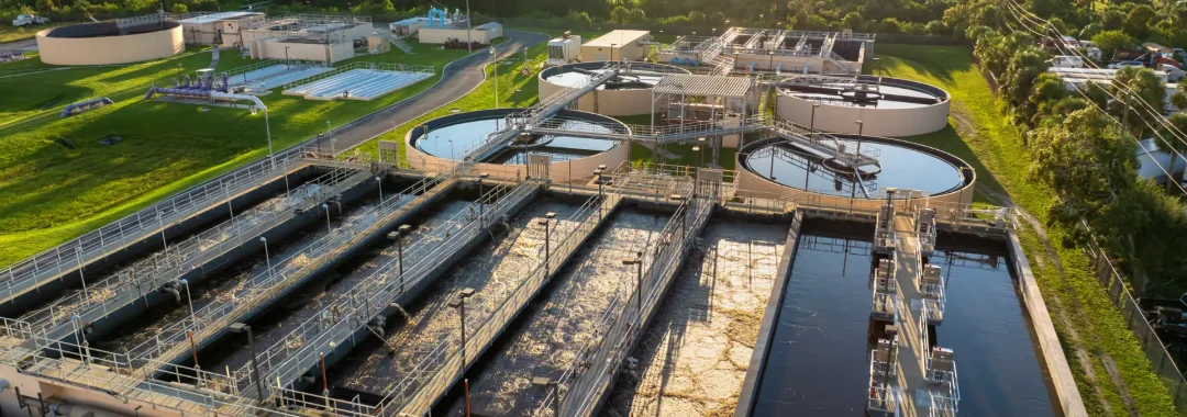 Sludge volume reduction system at industrial wastewater treatment plant using clarifiers and aeration tanks under sunset view.